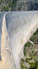 Towering Concrete Dam in a Lush Mountain Valley Under a Blue Sky