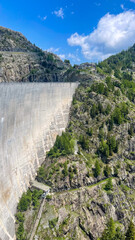 Towering Concrete Dam in a Lush Mountain Valley Under a Blue Sky