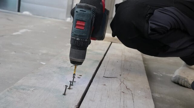 Close-up of a cordless power drill driving screws into wooden boards during construction and renovation work. Professional installation process, DIY home improvement, carpentry and repair concept. Det