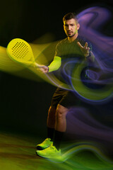 Man playing padel tennis with vibrant colors and dynamic movement in a dark setting