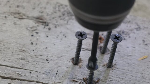 Close-up of a cordless power drill driving screws into wooden boards during construction and renovation work. Professional installation process, DIY home improvement, carpentry and repair concept. Det