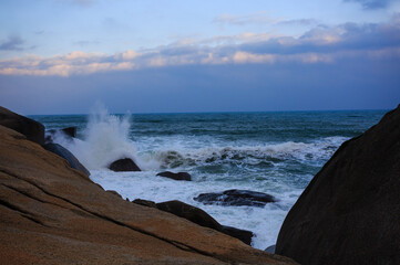 Fototapeta premium The scenery of Stone Park in Hainan, China, features emerald-green seawater crashing against the rocks, creating beautiful waves.