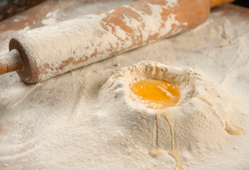 Close-up of a rolling pin and piles of flour with yolk on it