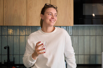 Smiling Woman Holding a Glass in Warm Kitchen Light