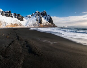 view of black sand beach with snow covered mountain in background