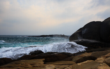 Obraz premium The scenery of Stone Park in Hainan, China, features emerald-green seawater crashing against the rocks, creating beautiful waves.
