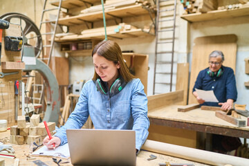 Young apprentice learning woodworking skills in a busy lumberyard
