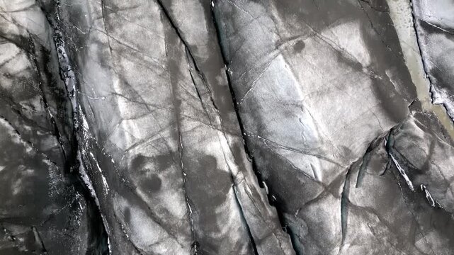 Cinematic aerial drone view of Sv&iacute;nafellsj&ouml;kull glacier tongue showing dramatic blue ice and volcanic ash textures in Iceland 4K.