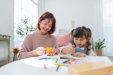 Fototapeta premium Mother and daughter spend time together crafting and learning at home in bright, sunny room