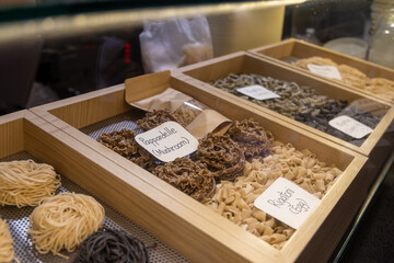 Assorted fresh handmade pasta displayed in rustic wooden boxes under warm lighting. Artisan Italian food concept. Culinary tradition and gourmet ingredients.