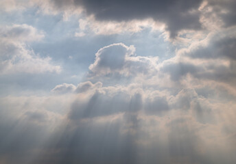 A dynamic sky filled with thick, dramatic clouds allows sunlight to stream through, creating beautiful rays of light and a moody atmosphere. Copy space.