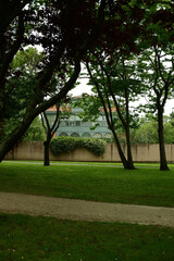 Park Ferrera in Aviles on a summer overcast day, featuring green lawns, trees, and historic buildings. Empty urban park with a calm and serene atmosphere