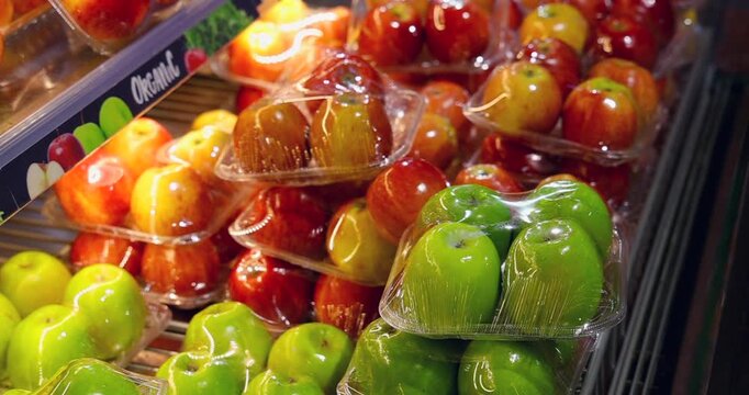 Variety of organic apples, red, green, and yellow, packaged on a brightly lit supermarket shelf. Healthy food, retail, and consumer choice concept. Fresh produce display.