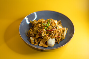 Spicy fried rice with pork and vegetables in blue bowl on yellow background