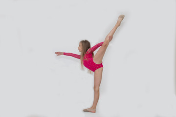 A young rhythmic gymnast in a bright pink leotard performs elements