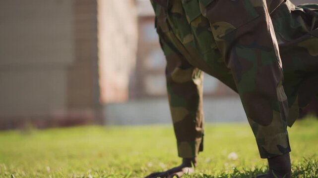Military Exercise Outdoors, Disciplined Soldier Training Outdoors In Camouflage Uniform During Pushups, Focused Military Personnel Engaging In Endurance Workout On Grass Field With Building Background
