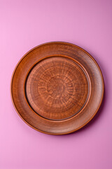 An empty round ceramic plate on a pink background as a kitchen utensil. An empty plate