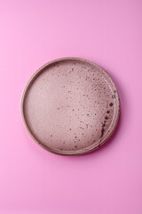 An empty round ceramic plate on a pink background as a kitchen utensil. An empty plate