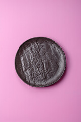 An empty round ceramic plate on a pink background as a kitchen utensil. An empty plate