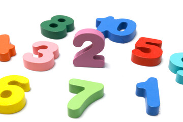 Colorful wooden numbers scattered on a white background. Ideal for education, math learning, kids activities, and teaching materials, close-up