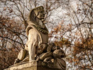 Ancient Egyptian Pharaoh Statue Standing in a Weathered Stone Garden Amid Autumn Trees