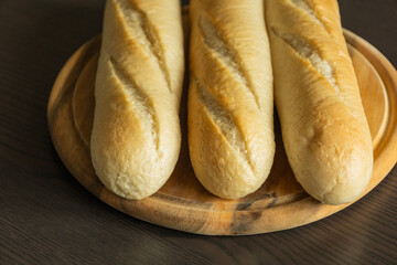 Three Small Bread Baguettes on Wooden Cutting Board