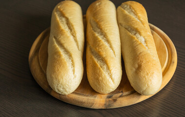 Three Small Bread Baguettes on Wooden Cutting Board