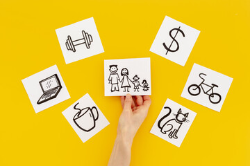 Hand is choosing Family card from many paper cards with hand drawing of different life activities. Life balance concept.