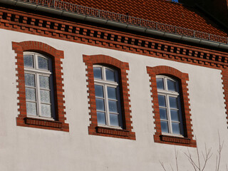 Facade of an old building with windows surrounded by brick frames, dogtooth course style