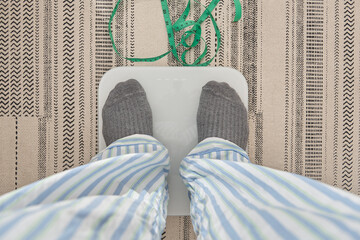 Person standing on a weighing scale, measuring tape lying nearby, focusing on health goals