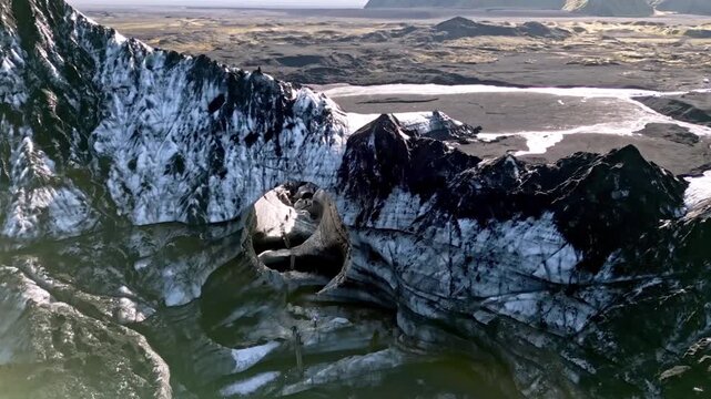 Cinematic aerial drone flight through Katla ice cave tunnel showing blue ice with black volcanic ash veins and green mossy mountains in Iceland 4K.
