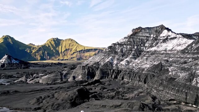 Cinematic aerial drone flight through Katla ice cave tunnel showing blue ice with black volcanic ash veins and green mossy mountains in Iceland 4K.