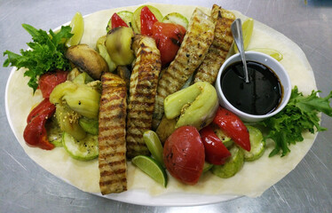 Baked sturgeon steaks with fresh salad greens, basil leaves and cherry tomatoes on a large white plate. delicious and healthy food for kids and adults. diet food. grilled vegetables next to the fish