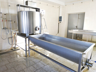 A cylindrical metal tank connected to a long rectangular bath. Dairy shop. Ripening and salting of cheeses and feta cheese. Cheese production.