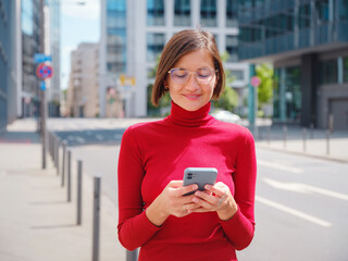 Beautiful woman in walking in Frankfurt on spring day and holding mobile phone. Urban lifestyle concept. Check social networks, send sms or book hotel, exuding confidence and professionalism