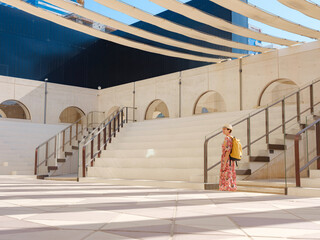 Young woman exploring Qasr Al Hosn Park in Abu Dhabi. Surrounded by lush greenery and historical landmarks, she enjoys the serene atmosphere and Emirati heritage in heart of city.