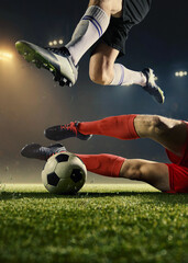 Football sliding tackle moment with airborne legs and ball on night stadium pitch. Concept of defensive play, match intensity, competitive duel, sport advertising, professional athleticism. © Lustre Art Group 
