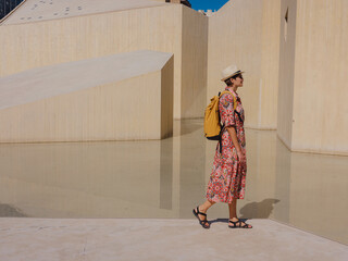 Young woman exploring Qasr Al Hosn Park in Abu Dhabi. Surrounded by lush greenery and historical landmarks, she enjoys the serene atmosphere and Emirati heritage in heart of city.