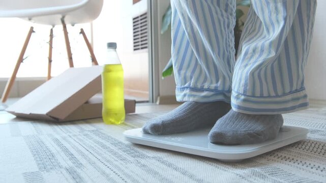 Overweight person in pajamas weighing on a scale and dropping a measuring tape, quitting the diet