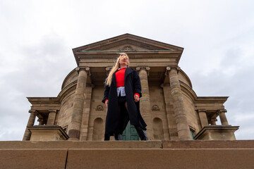 Beautiful blond hair woman standing in the wind in front of medieval building