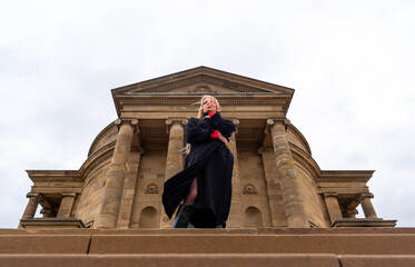Young woman elegant and well dressed standing in front of a medieval chapel