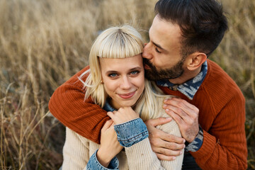 Couple enjoying a relaxing moment together on the grass and taking a selfie with a mobile phone camera  during a sunny day in a field
