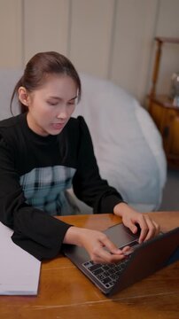 Frustrated Asian woman holding a declined credit card during online shopping. She faces financial stress and insufficient funds due to the economic crisis, representing the silent struggle.
