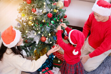 A father, mother, and a young girl celebrating Christmas, smiling happily. Happy New Year, with a Christmas tree.