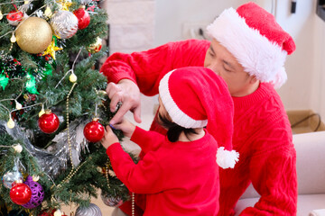 A man and a young girl celebrating Christmas and New Year with a Christmas tree.