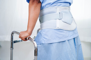 Asian senior pain back wearing elastic support belt with walker.