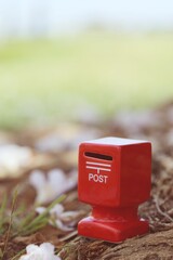 Red mailbox with pink flower fall on ground nature background