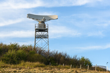 View of a radar antenna for the surveillance of maritime traffic on the top of a cliff on a sunny spring day
