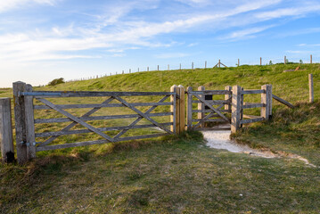 Wooden gate and stile along a path through grassy fields in the English countryside in spring