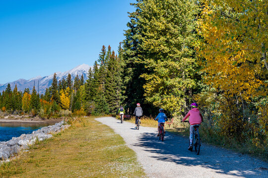 People cycling along the Bow River walking trail in autumn. Canmore, Alberta, Canada. Higashikawa Friendship Trail.